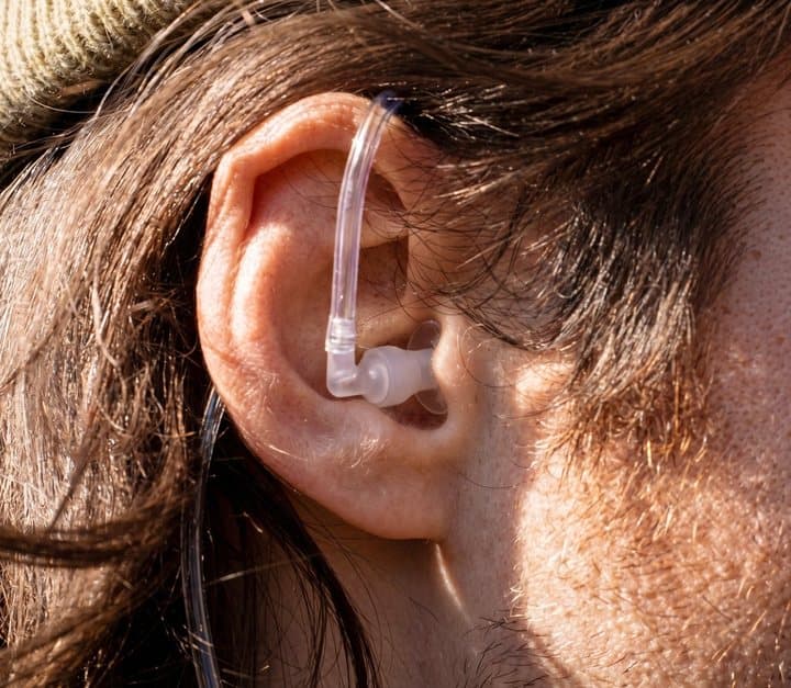 Close-up of a clear Air-Tube earpiece and silicone tip sitting in a person's ear