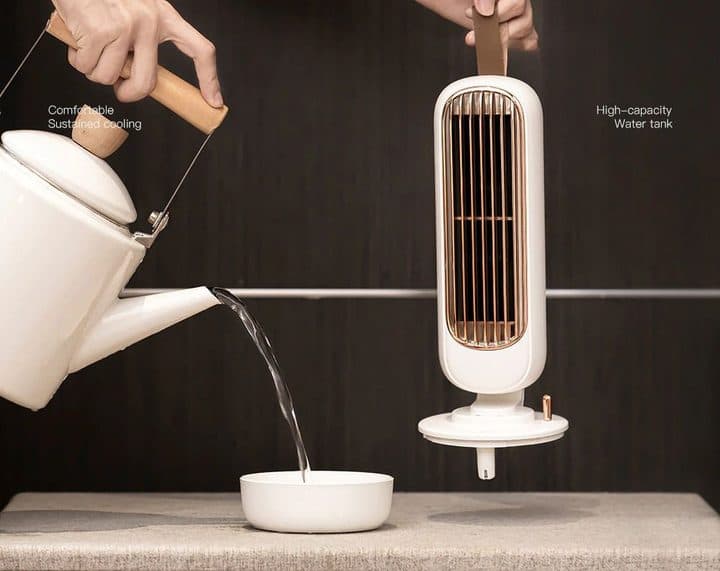 White AirCooly tower lifted off its base while water is poured from a kettle into a bowl, labelled high-capacity water tank