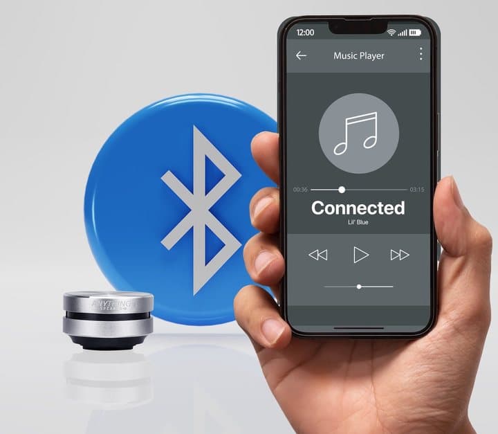 Hand holding a phone showing Connected next to a silver Anything Speaker and a Bluetooth logo