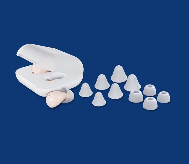 Audien charging case with two hearing aids and a set of white silicone ear tips in several sizes