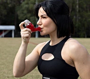 A woman in sports clothing breathing out through the Better Breathing Sport device outdoors