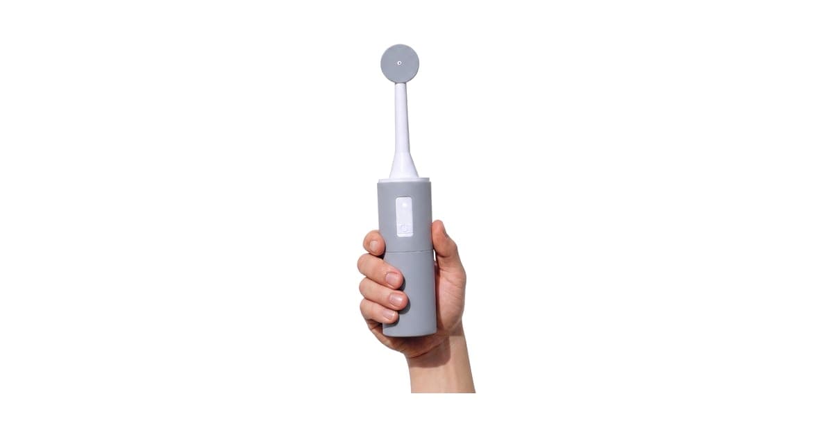 Grey BumBum portable bidet with its white fold-out nozzle extended, held in a hand