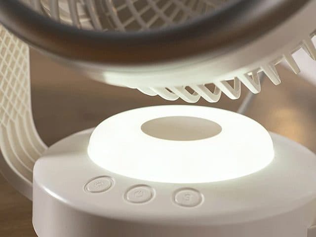 Close-up of the CoolSwing base glowing white as a night light, with three buttons on the front