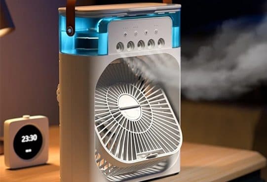 CoolTime box fan on a bedside table with buttons on top, a lit blue water tank and mist blowing out over the fan grille