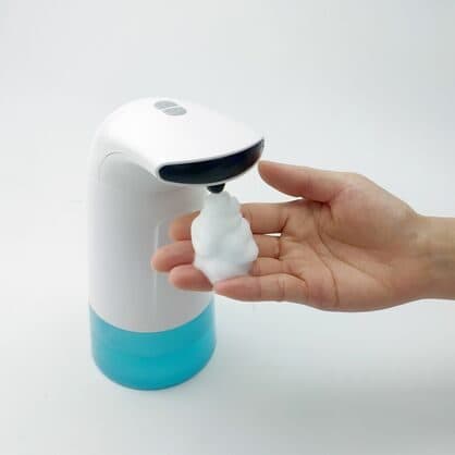 White touchless soap dispenser with a blue base dispensing foam onto a hand