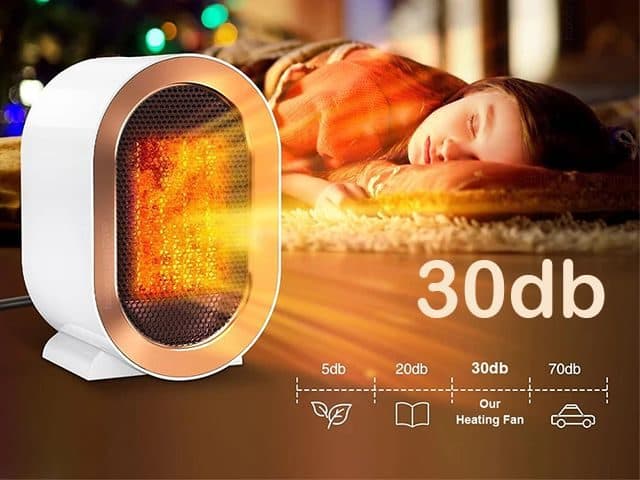 CozyTime Pro heater glowing beside a girl asleep on a rug, with a noise scale comparing 30 dB to a book and a car