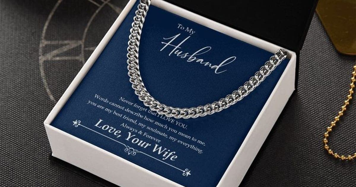 Silver-tone Cuban Link Chain on a navy To My Husband card signed Love, Your Wife, in an open black and white gift box on a dark table