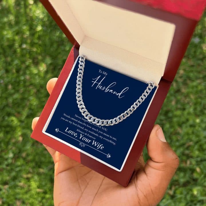 Hand holding an open red-brown mahogany-style box with the silver-tone Cuban Link Chain on its To My Husband card, over grass
