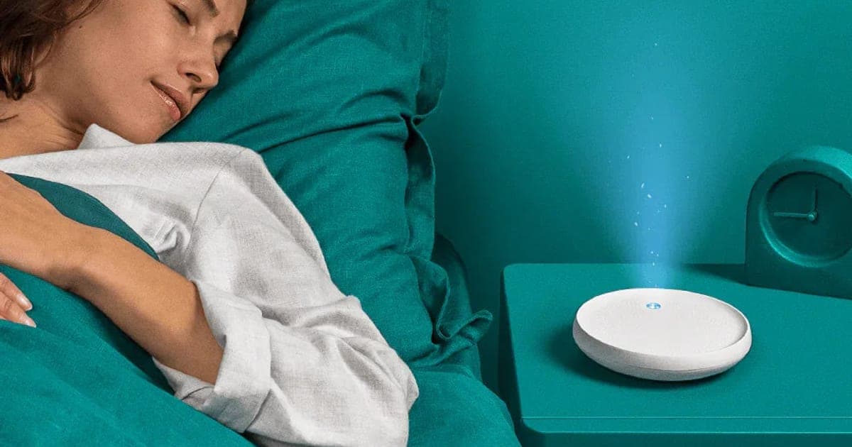 Woman asleep in bed beside a white Dodow sleep light projecting a soft blue halo upward from her nightstand