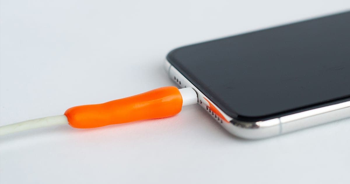 Orange FixIts mouldable plastic wrapped around a frayed phone charging cable where it meets the plug