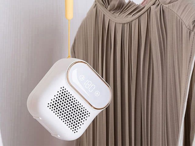FridgeSan Pro hanging on a yellow cord in front of a pleated olive dress in a wardrobe