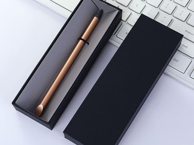 Rose gold metallic FutureX Pen in an open black gift box on a white keyboard