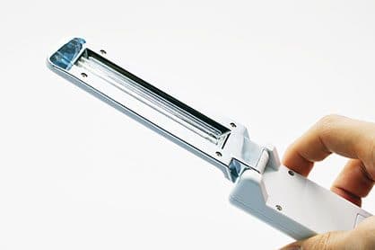 A hand holding the GermCide X wand with its lamp head open, showing a single UV tube behind a clear window