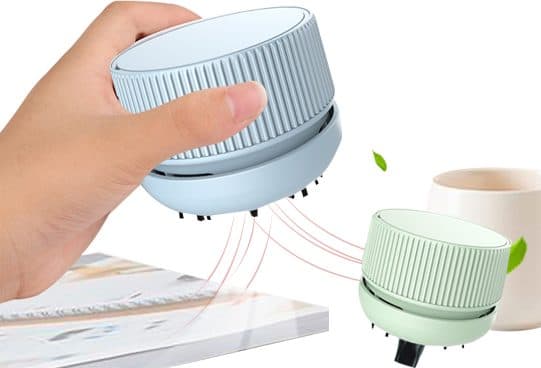 Pale blue round HandyVacuum held over an open book with suction lines, and a mint green HandyVacuum beside a cream mug