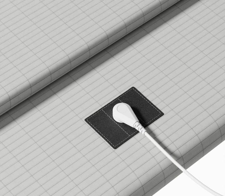 Close-up of the black snap connector patch and white cord on the grey Heal Naturally grounding sheet