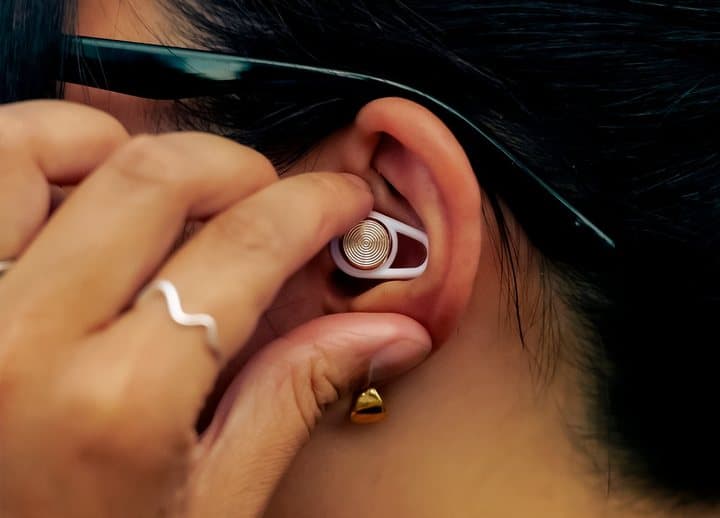 Woman inserting a white Hears earplug into her ear with her fingers
