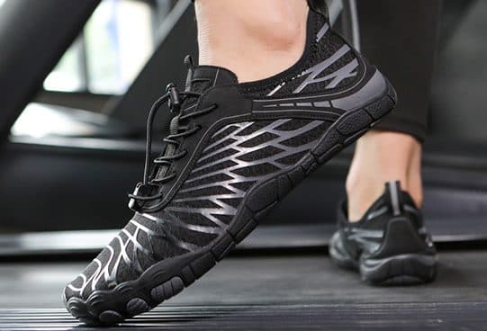 Close view of black HikeGrip Pro shoes with silver striped mesh uppers, toggle laces and toe-shaped rubber soles on a treadmill belt