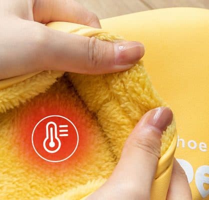 Fingers pulling open the yellow HyperShoes to show a thick fluffy fleece lining with a heat icon