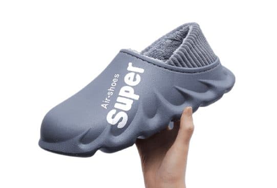 Hand holding a grey HyperShoes slipper clog with a moulded shell, wavy sole, grey fleece lining and Super Air-shoes text