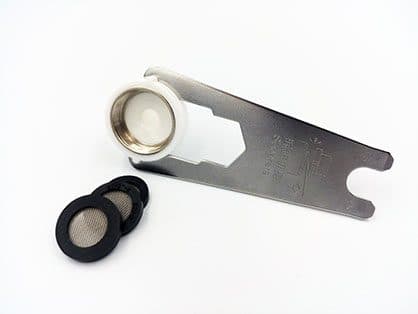 Flat metal wrench holding a white threaded adapter, with three black rubber washers with mesh filters beside it