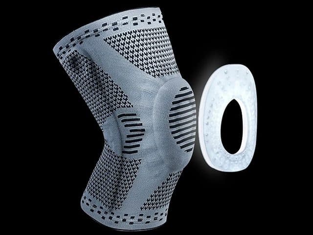 KneeBoost Pro sleeve beside a white oval silicone kneecap ring with raised dots