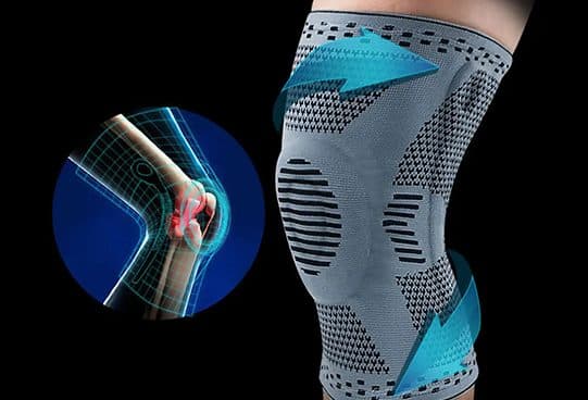 KneeBoost Pro grey knitted sleeve with a raised kneecap ring and black patterned zones, worn on a leg against a black background
