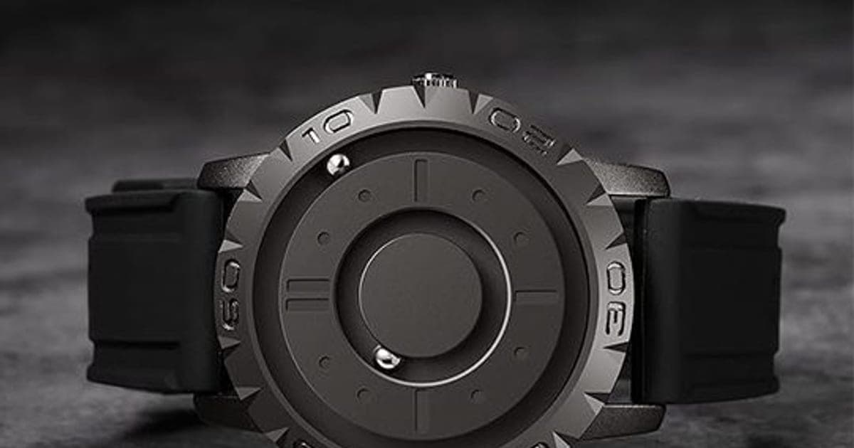 Gunmetal MagWatch with a toothed bezel numbered in tens and two silver steel balls on its dial tracks, on a black silicone strap