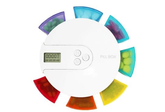 Round white MedReminder with an LCD showing 00:00 and four alarm markers, H, M and S buttons, and purple, blue, green, yellow, orange and red compartments of pills