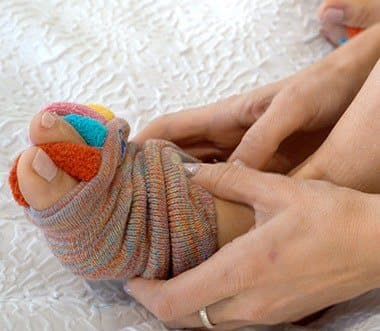 Hands easing a My Happy Feet Sock spacer between the toes of a foot