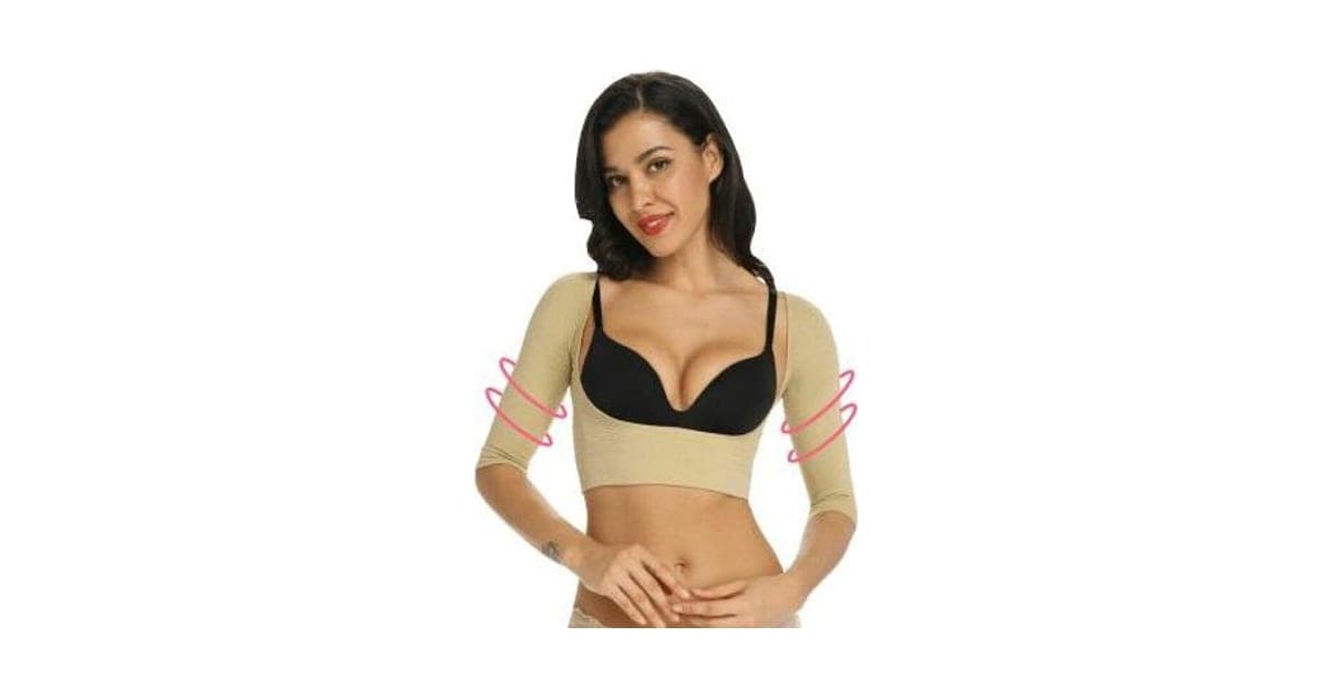 Woman wearing a beige MyCorrector Pro cropped shapewear top with three-quarter sleeves over a black bra, with pink arrows around the upper arms