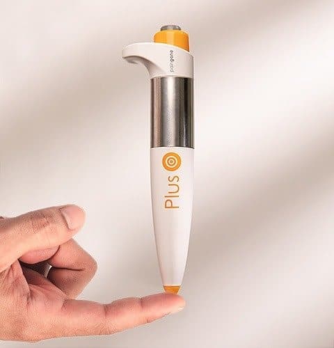 Paingone Plus pen balanced upright on a fingertip to show its size