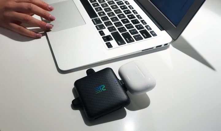 Rush Charge Universe charging an earbuds case on a desk next to a laptop