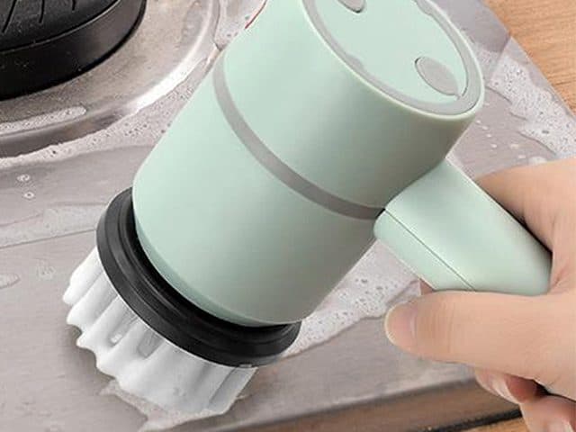 ScrubClean Pro with a white bristle brush head scrubbing a soapy stainless steel hob