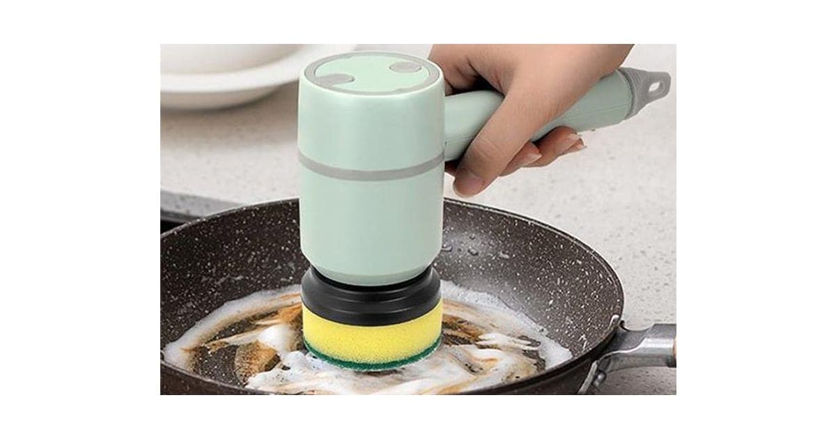 Mint green ScrubClean Pro spin scrubber with a yellow and green sponge head cleaning a greasy frying pan, held by a hand