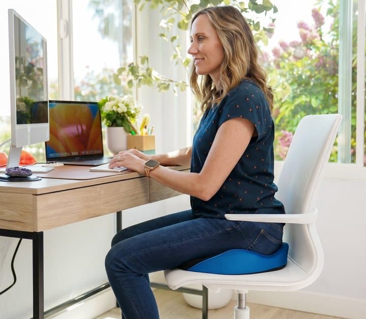 Woman working at a desk sitting on a Serenesitz cushion
