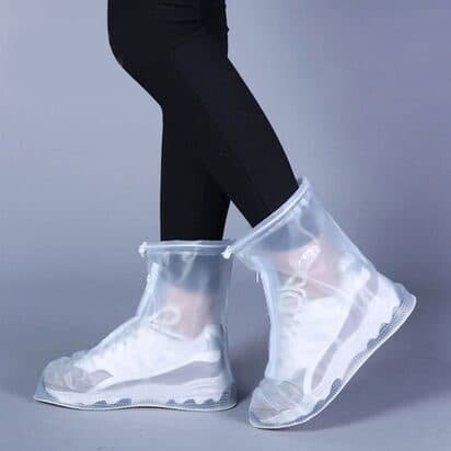 Clear ankle-high ShoesCover Max covers worn over white trainers against a grey background