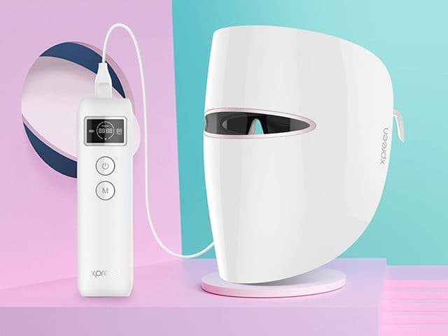 White LED face mask marked Xpreen on a stand, connected to a white controller with a digital display and power and mode buttons