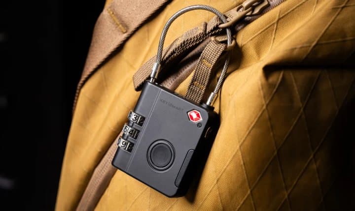 KeySmart SmartLock locked onto the zip of a tan travel backpack