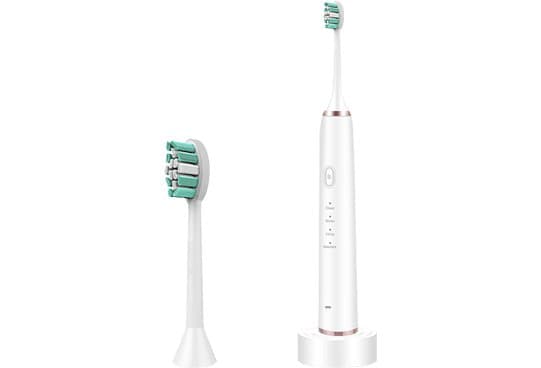 White SonicX PRO toothbrush with buttons down the handle, standing on a small base beside a spare green and white head
