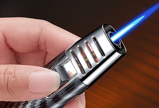 Close-up of fingers holding the StormFlame Pro, with slotted chrome guard around a blue jet flame