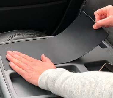 Hand smoothing a black silicone grip mat onto the Stupid Car Tray