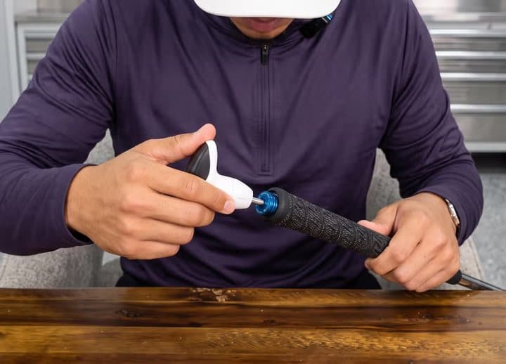 Man sliding a SwitchGrips grip onto a club shaft using a white fitting tool