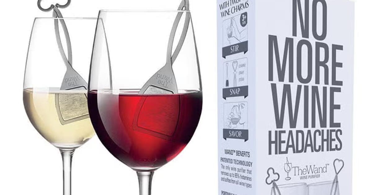 Two wine glasses of white and red wine with silver PureWine wands inside, beside a box reading No More Wine Headaches