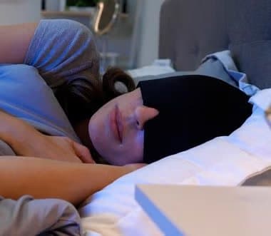 Woman lying in bed wearing a TheraICE cap over her eyes