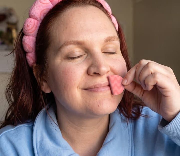 Woman in a headband peeling a pink mouth strip from her lips