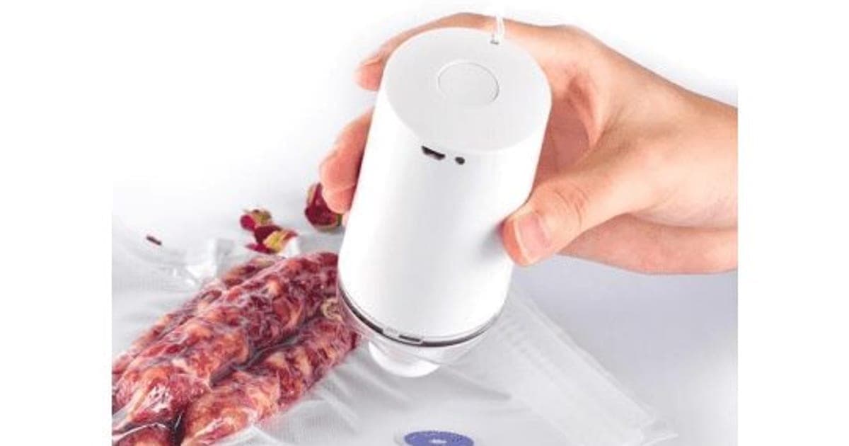 A hand holding a white Vacuumer Max pump on the valve of a clear bag of sausages, drawing the air out