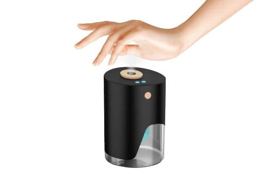 Hand held over the black VapeSan Pro with a fine mist rising from the round nozzle on top and two blue indicator lights