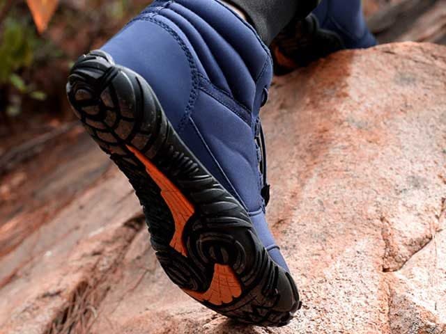Navy VentureShoes Pro gripping a reddish rock on a hillside, its lugged sole and orange inserts visible