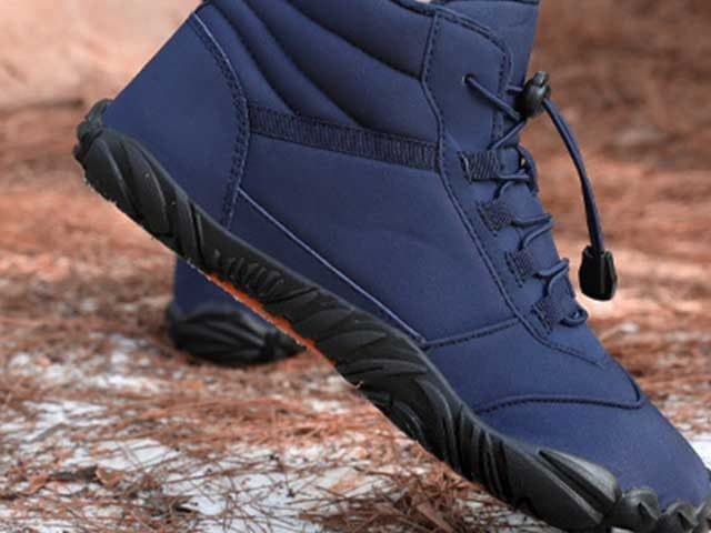 Close side view of a navy VentureShoes Pro high-top with toggle laces on pine needles and light snow