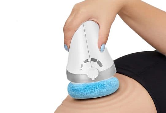 Hand holding the white VibraContour Pro massager with a speed dial and blue cloth head on a thigh